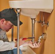 Plumber tightens a bathroom sink's drain line